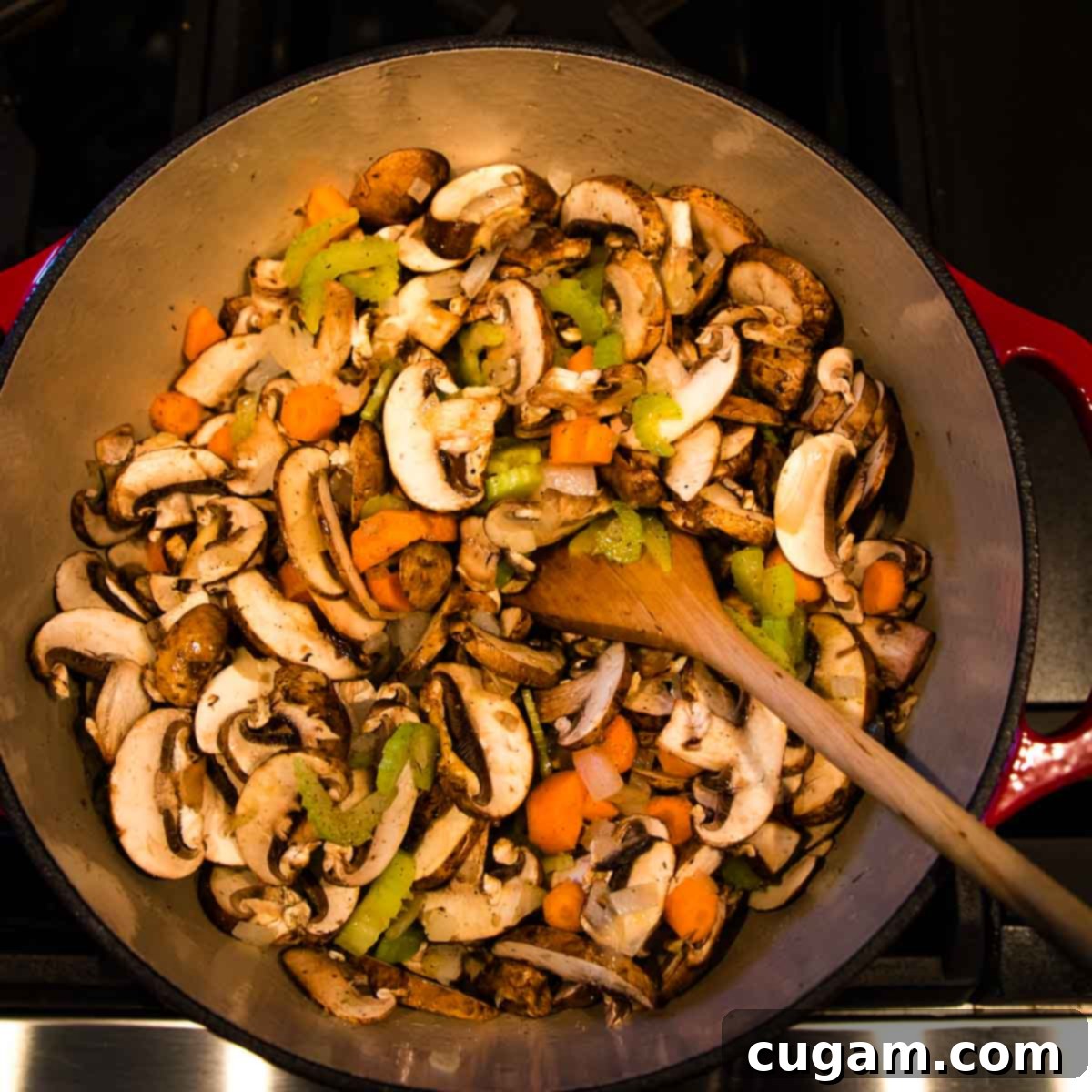 Mushrooms, onions, carrots and celery cooking in a dutch oven.