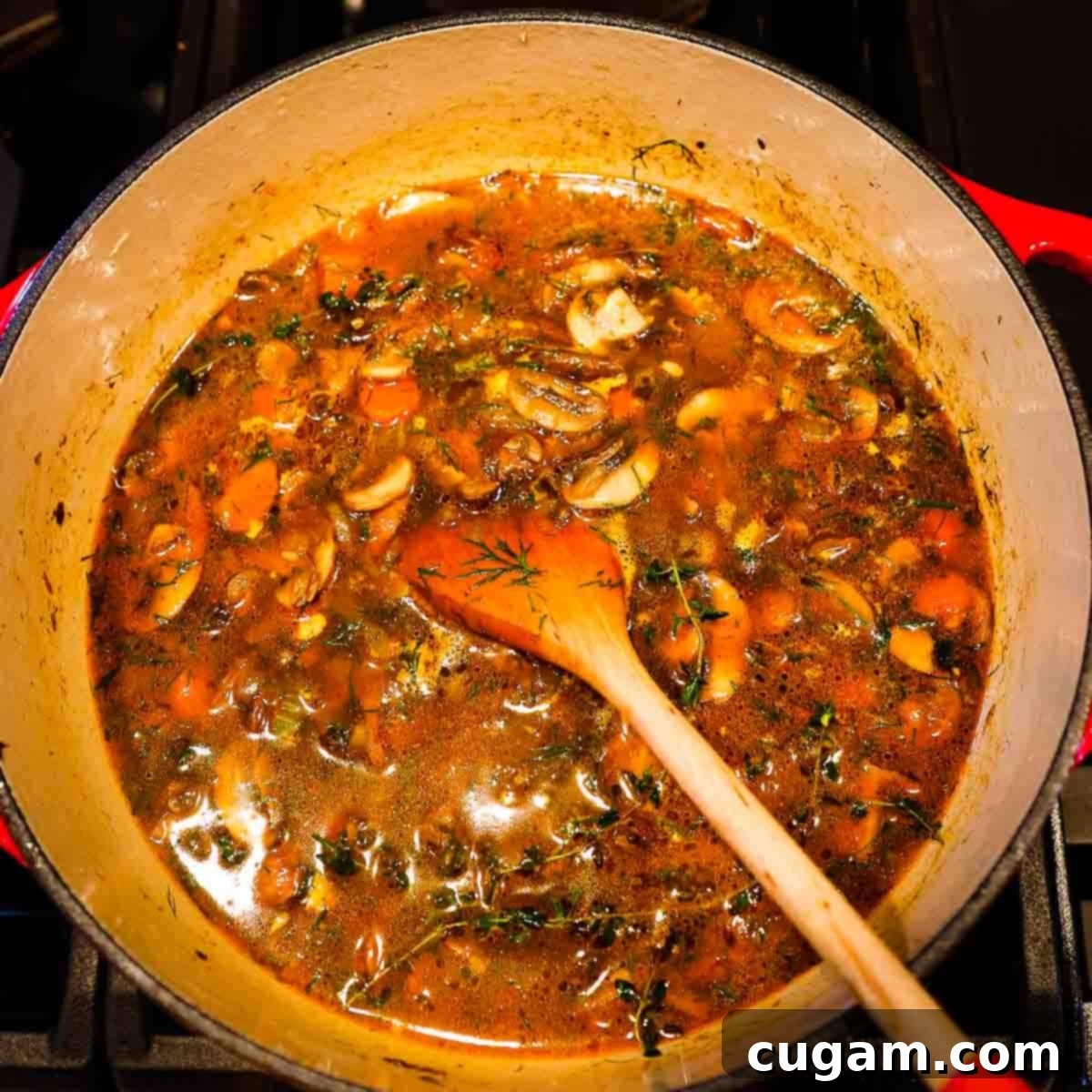 Mushrooms, carrots, celery and onions in a rich broth cooking in a dutch oven.