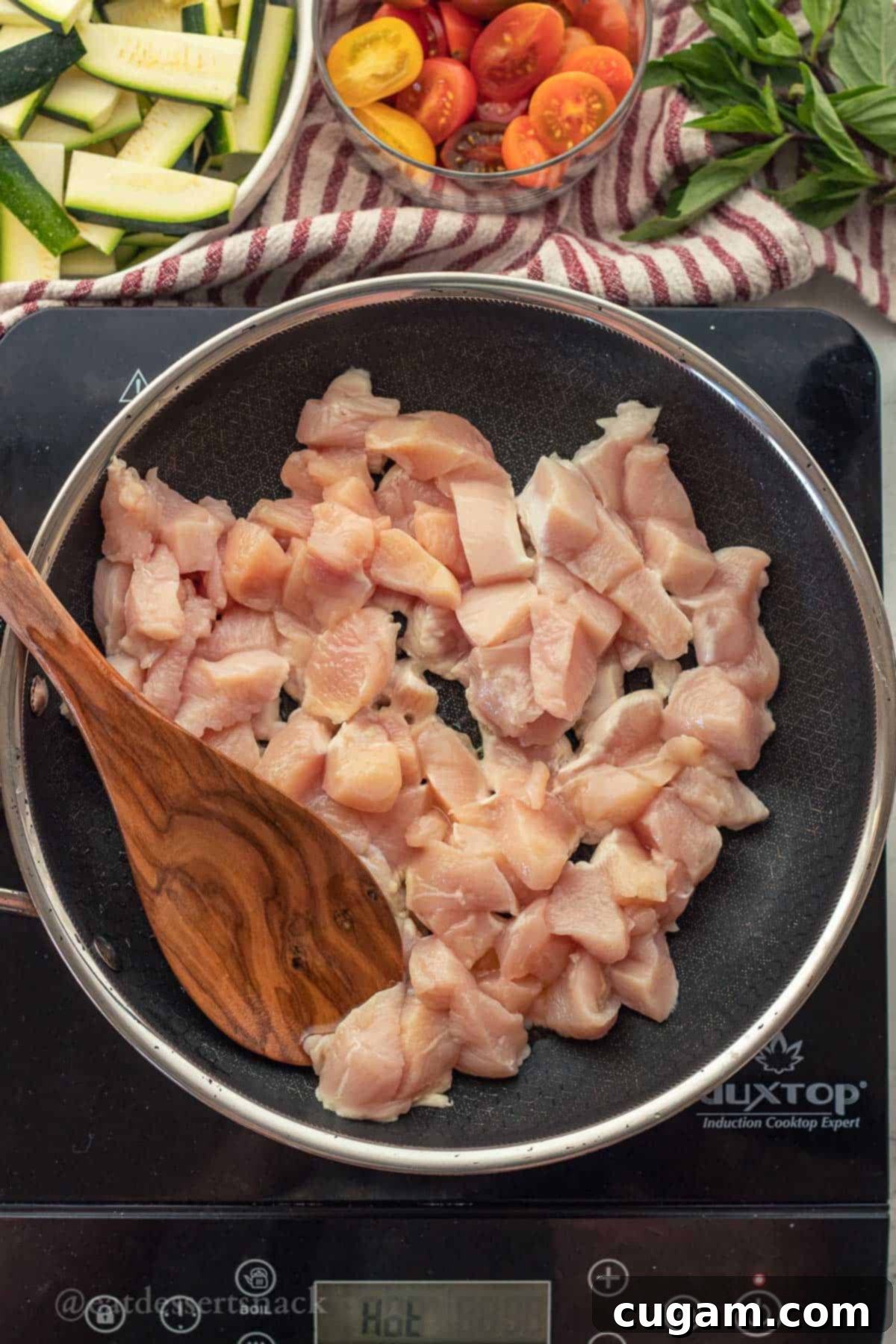 Savory Chicken Zucchini Tomato Skillet 4 Raw, diced chicken breast pieces in a metal pan, ready to be sautéed for the Italian chicken zucchini and mushroom skillet recipe.