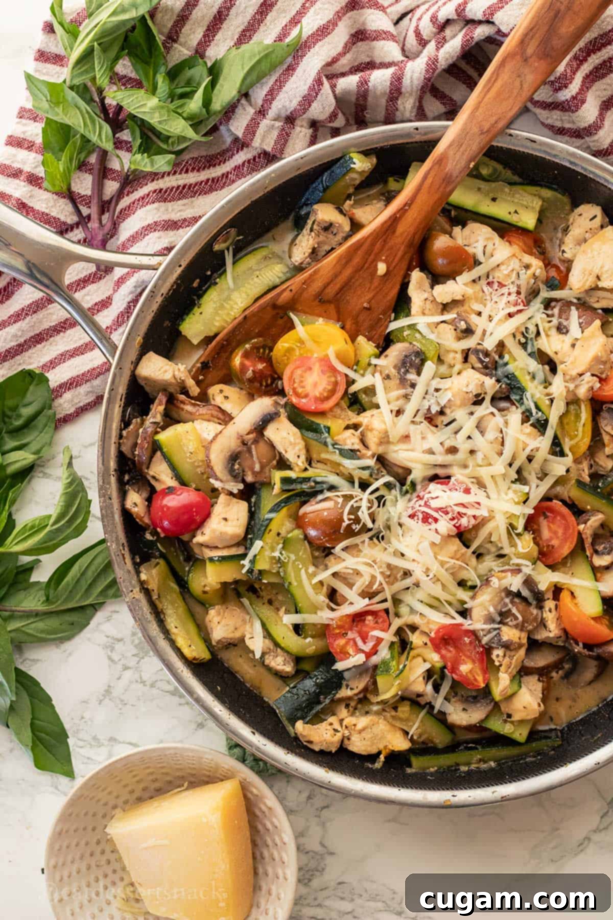 Savory Chicken Zucchini Tomato Skillet 7 The finished Italian Chicken Zucchini Mushroom Skillet, cooked and garnished with fresh herbs and Parmesan, served in a metal pan with a wooden spoon.