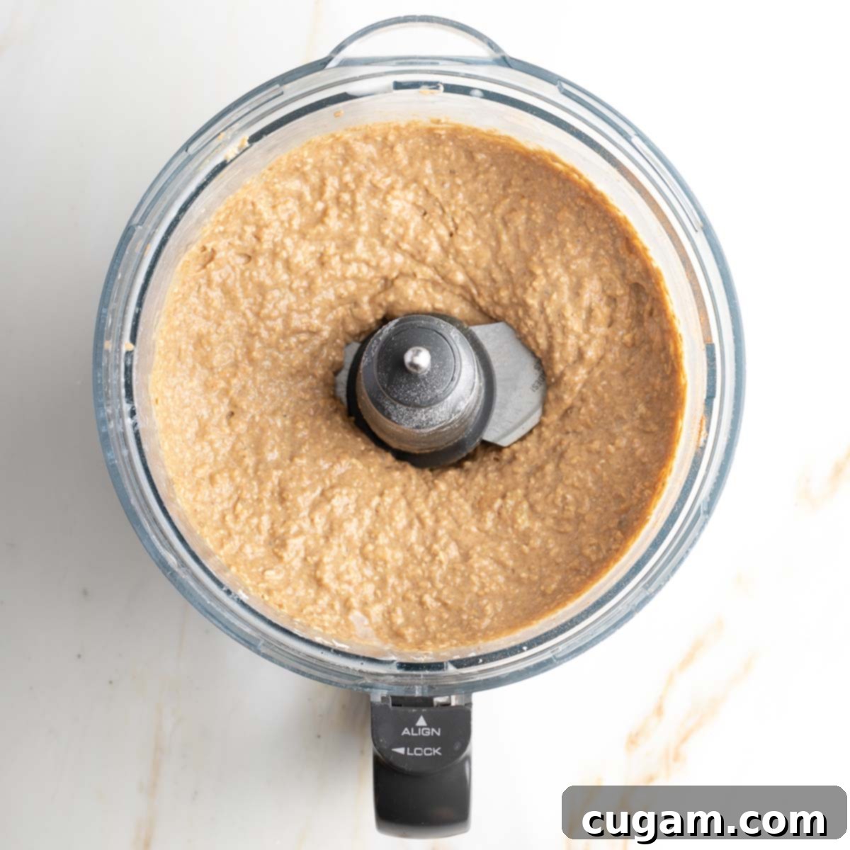 Thick, blended banana muffin batter in the bowl of a food processor, ready for chocolate chips. 