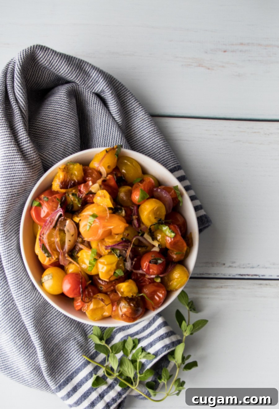 Beautiful bowl of roasted tomatoes with fresh oregano garnish.