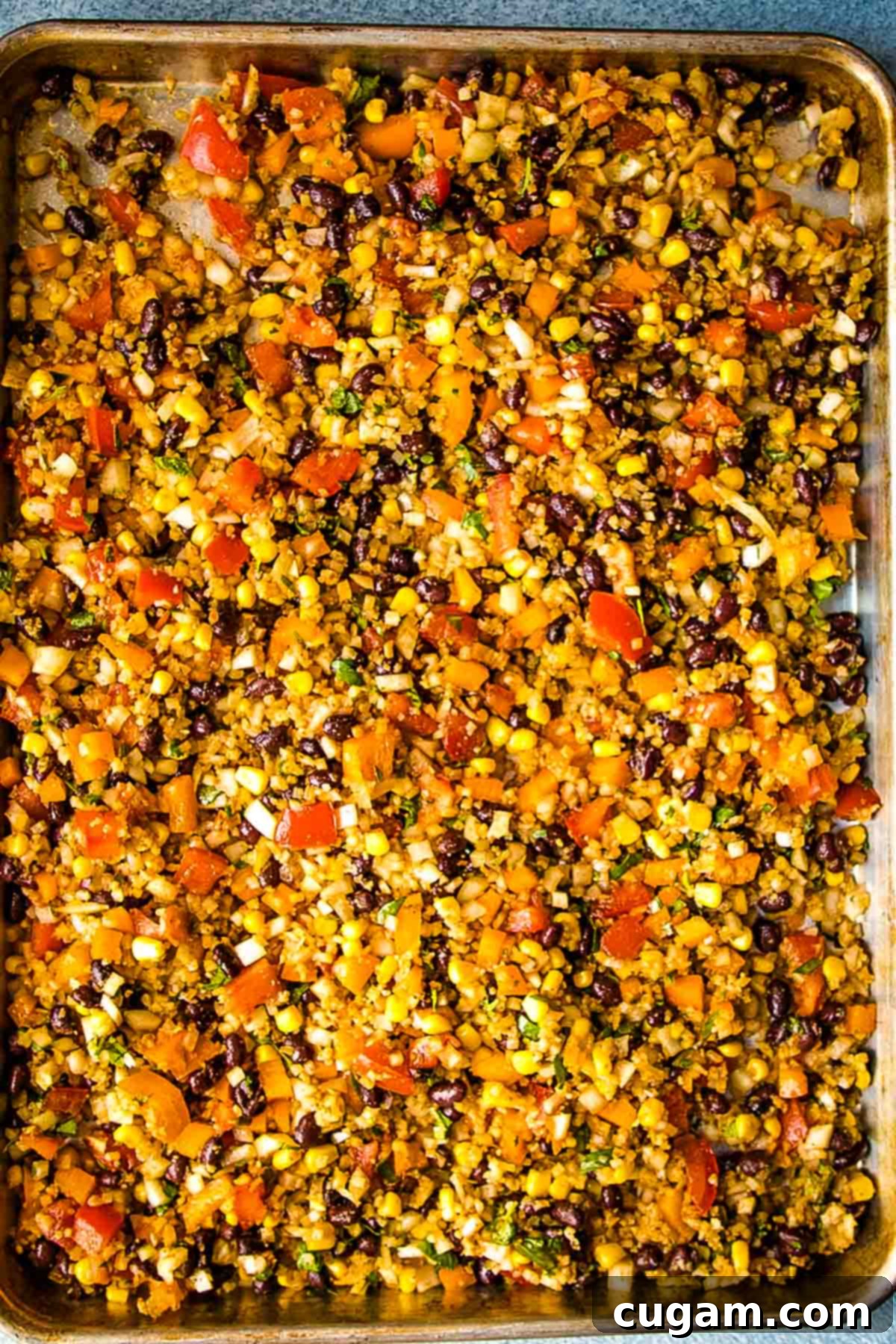 Cauliflower Rice on a sheet pan with mexican spices, tomatoes, bell peppers, black beans, corn and cilantro.