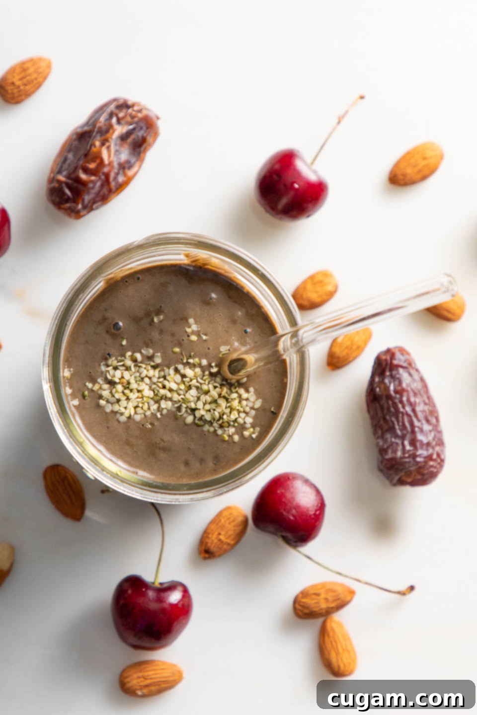 Cocoa Cherry Indulgence 2 Chocolate smoothie with hemp seeds sprinkled on top and dates, cherries and almonds on the counter.