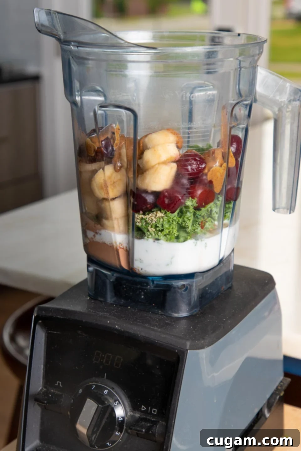 Cocoa Cherry Indulgence 4 Blender full of smoothie ingredients: bananas, cherries, kale, almond milk, almond butter, cacao powder, hemp seeds.