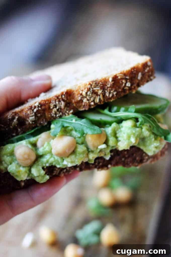 Close-up of a Smashed Chickpea Avocado Feta Sandwich, held in hand, showcasing the delicious filling and fresh ingredients.