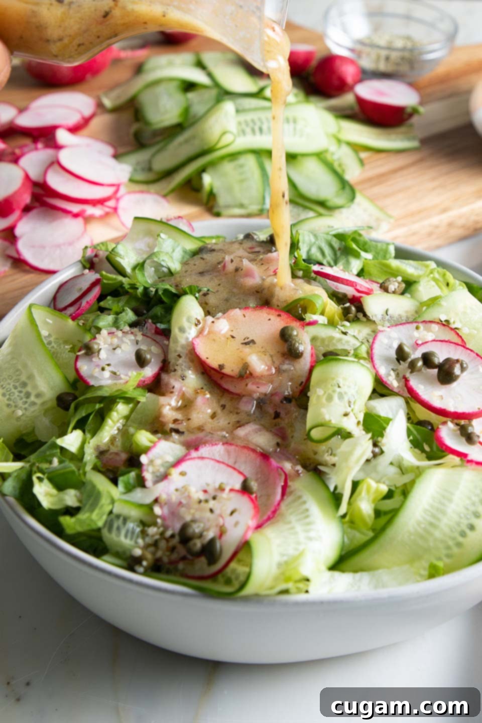 A small jug of homemade easy everyday salad dressing positioned alongside a bowl of vibrant green salad, perfectly complementing the fresh meal.