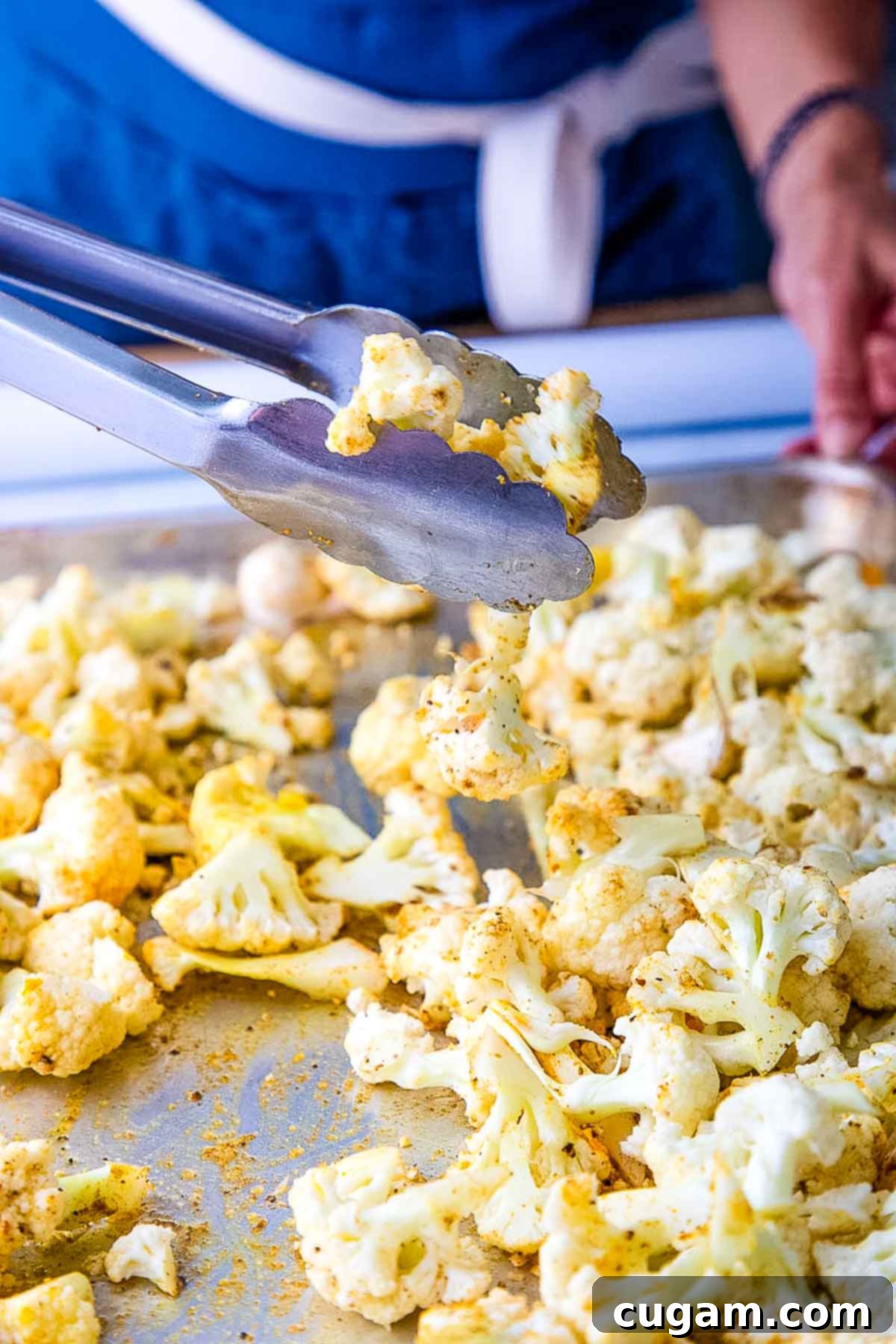 Roasting cauliflower florets and garlic, tossing with tongs.
