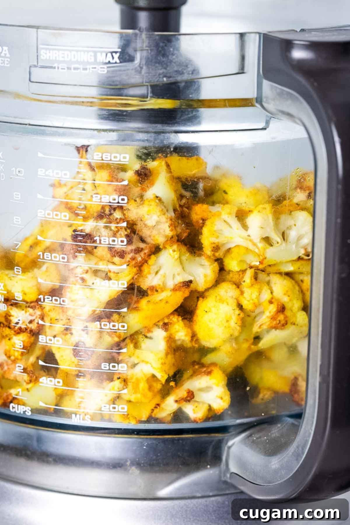 Roasted cauliflower florets in the bowl of food processor.