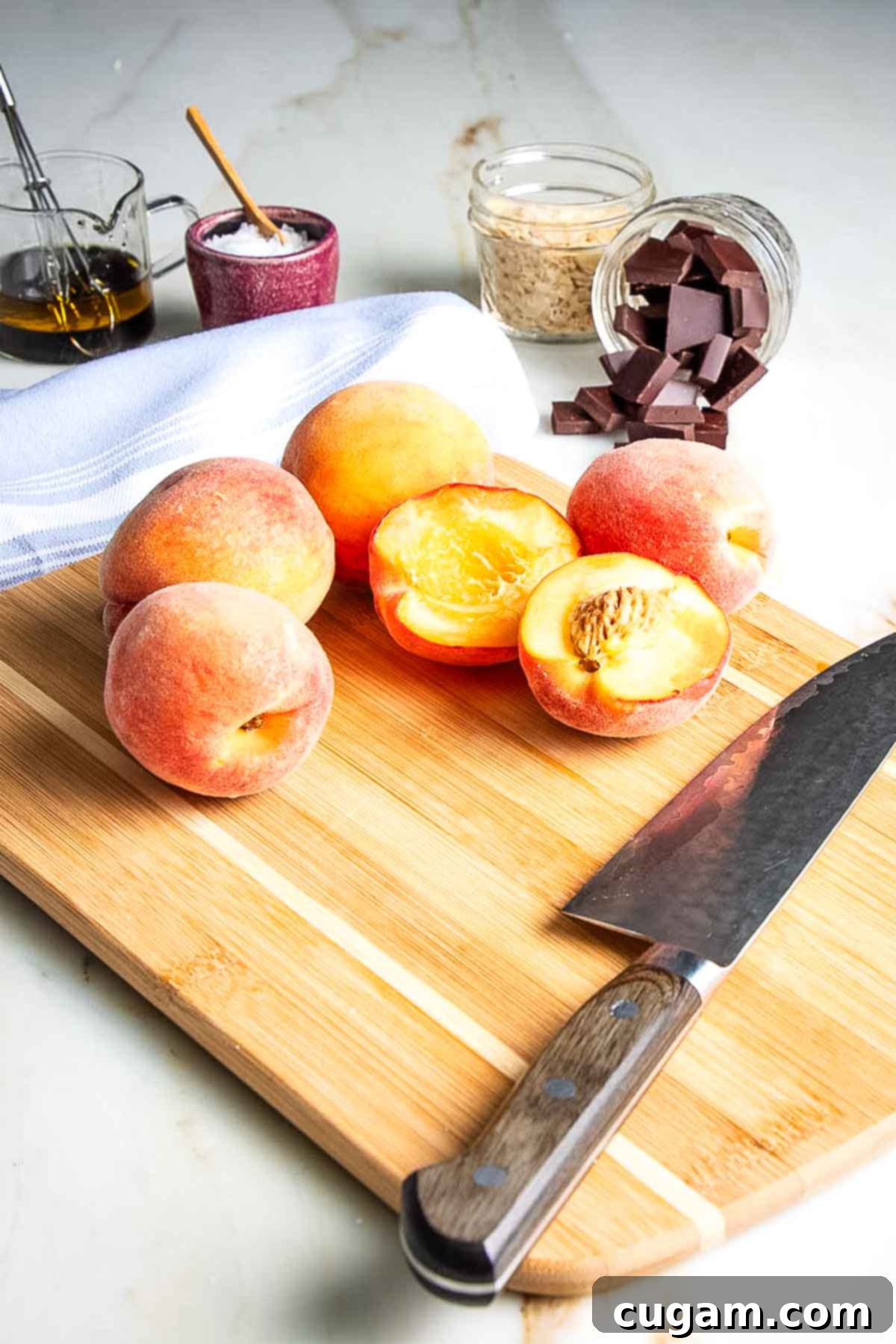 Cutting peaches in half on a cutting board, preparing for grilling.