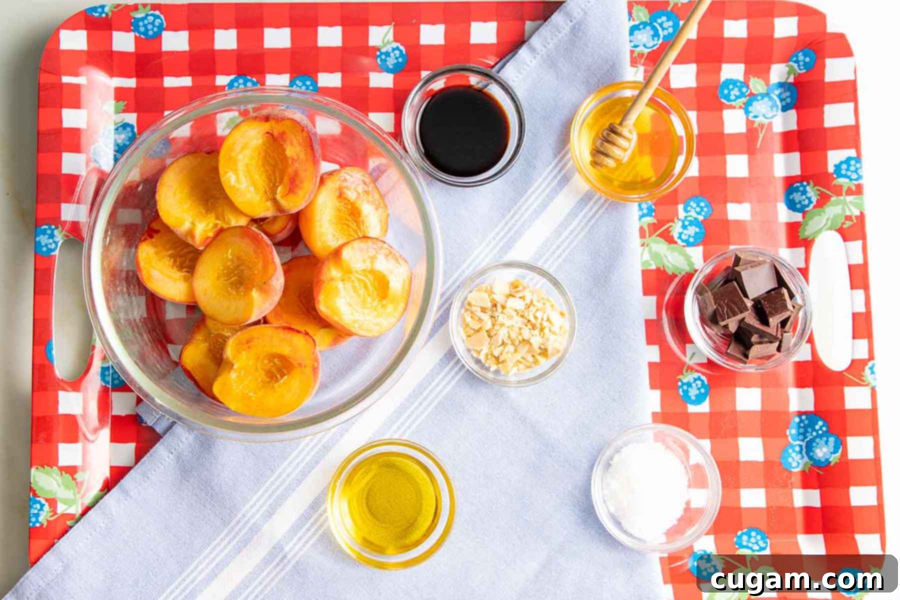 Bowl of halved peaches, small dishes with honey, almonds, olive oil, chocolate chunks, sea salt. Ingredients prepped.