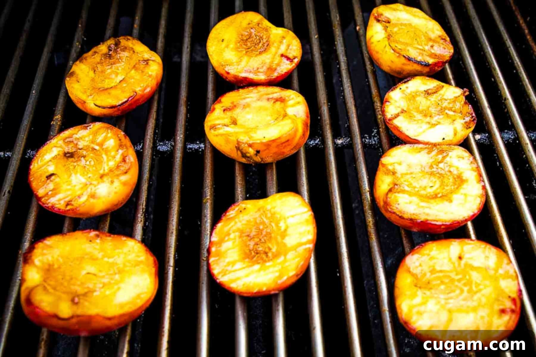 Halved peaches, cooking on a grill, skin side down.