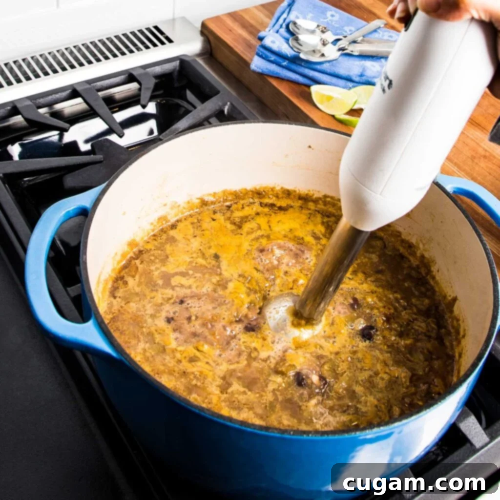 Vegetable broth being poured into the pot with black beans and other ingredients.