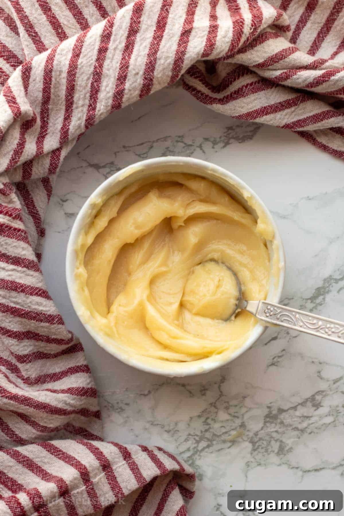 White bowl of mixed vanilla honey butter on marble countertop.