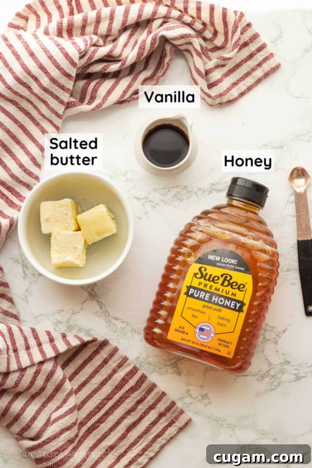 Ingredients for honey butter in glass dishes on marble countertop with red striped towel.