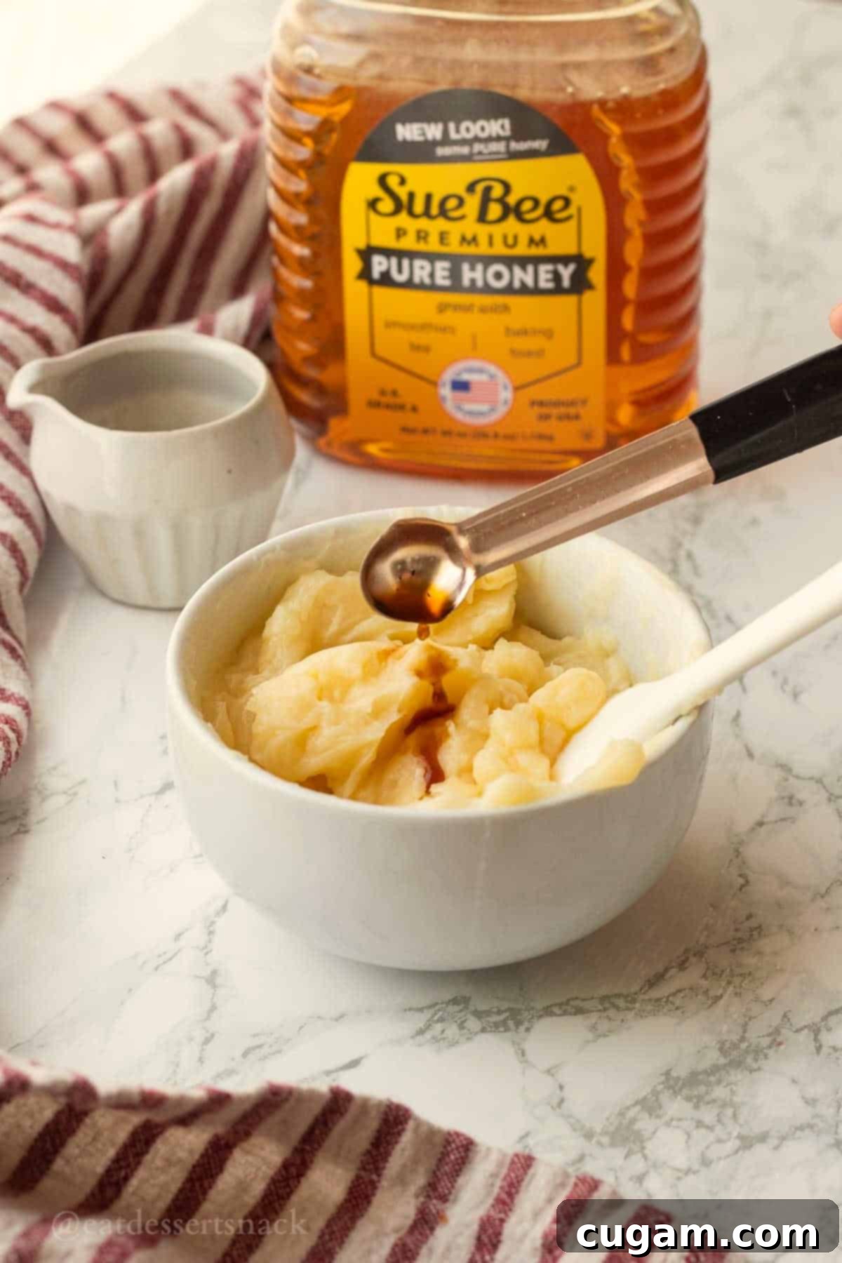 Pouring vanilla into white bowl of softened butter.