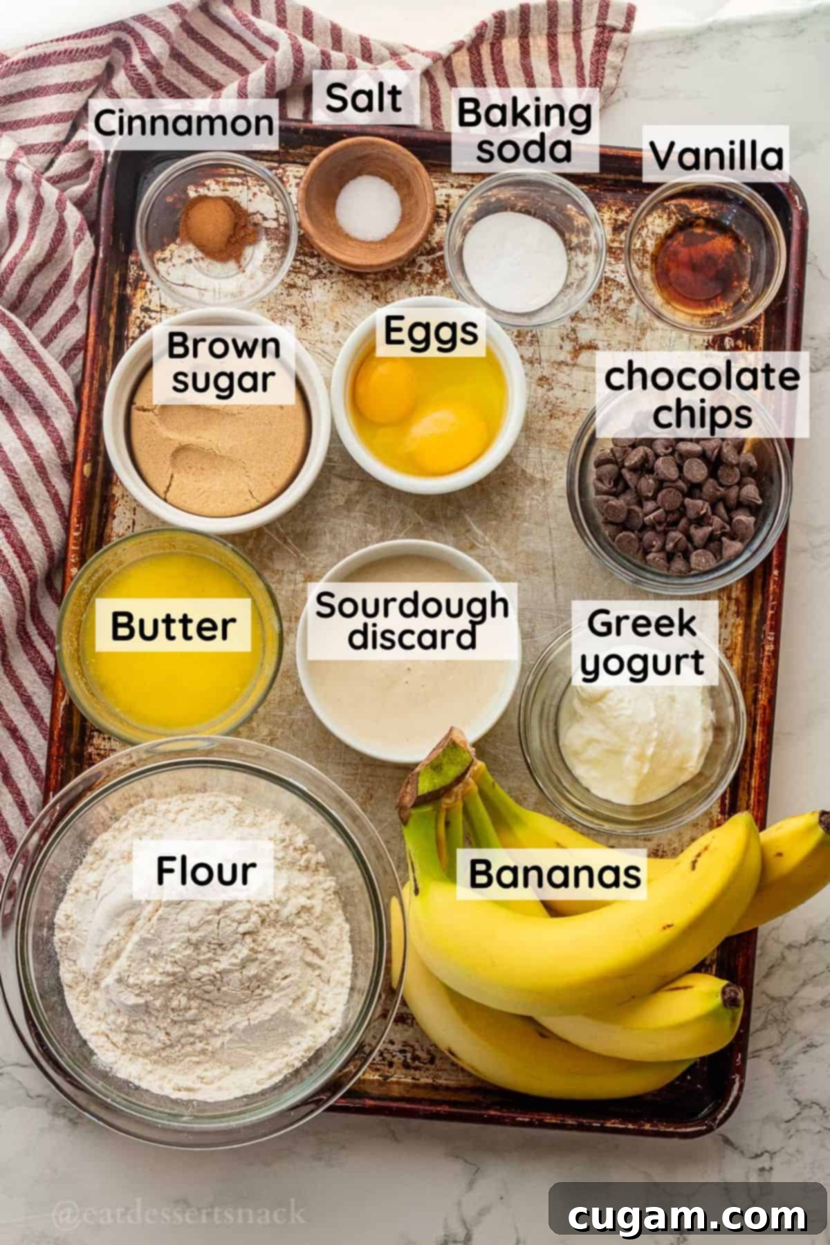 Elevated Sourdough Banana Bread 3 All ingredients for sourdough discard banana bread laid out in glass bowls on a metal baking sheet, clearly labeled.