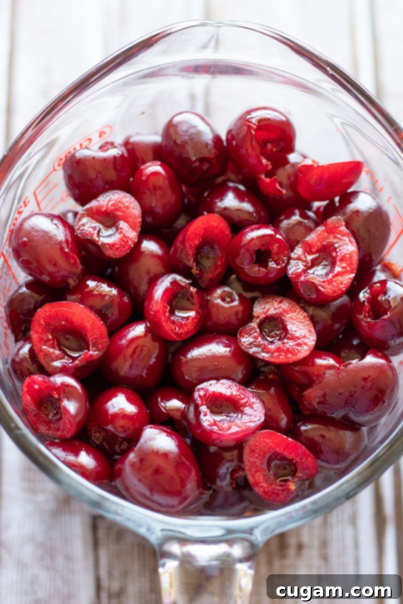 Raw pitted cherries in glass measuring cup for cherry pie filling.