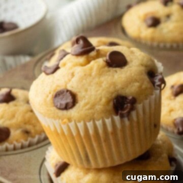 Tilted banana muffin in muffin wrapper on muffin tin.