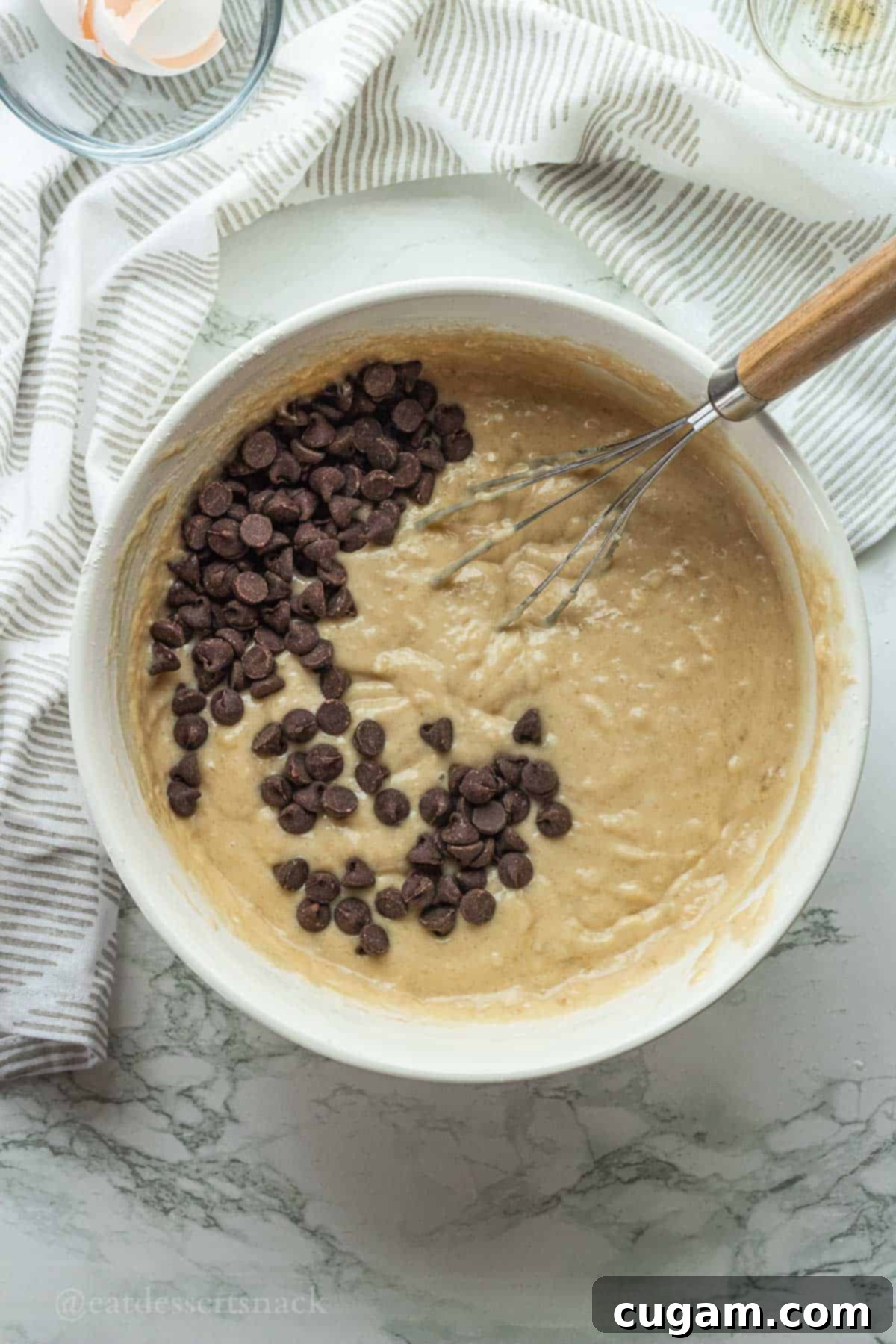 Sourdough discard muffin batter in bowl with whisk and chocolate chips.