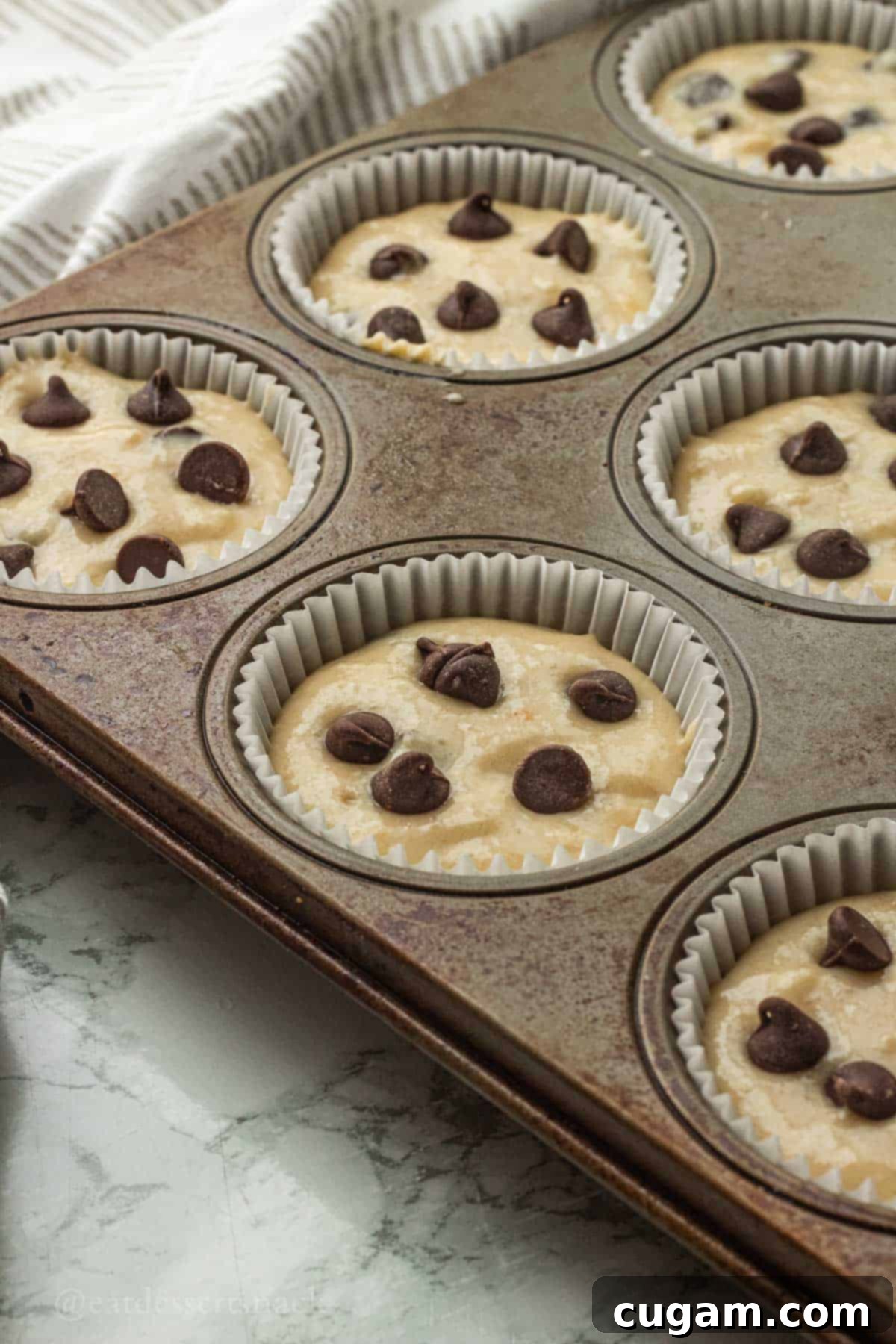 Raw banana muffin batter in muffin wrappers in muffin tin.