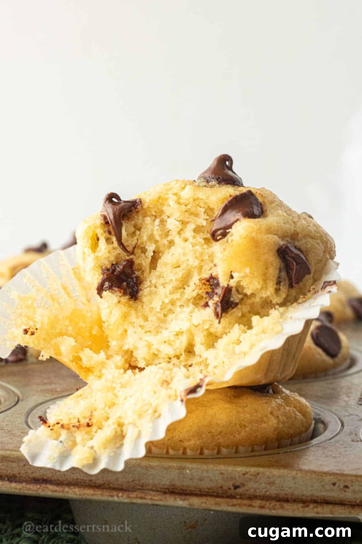 Half of a banana muffin in muffin wrapper, showing its fluffy interior and chocolate chips.
