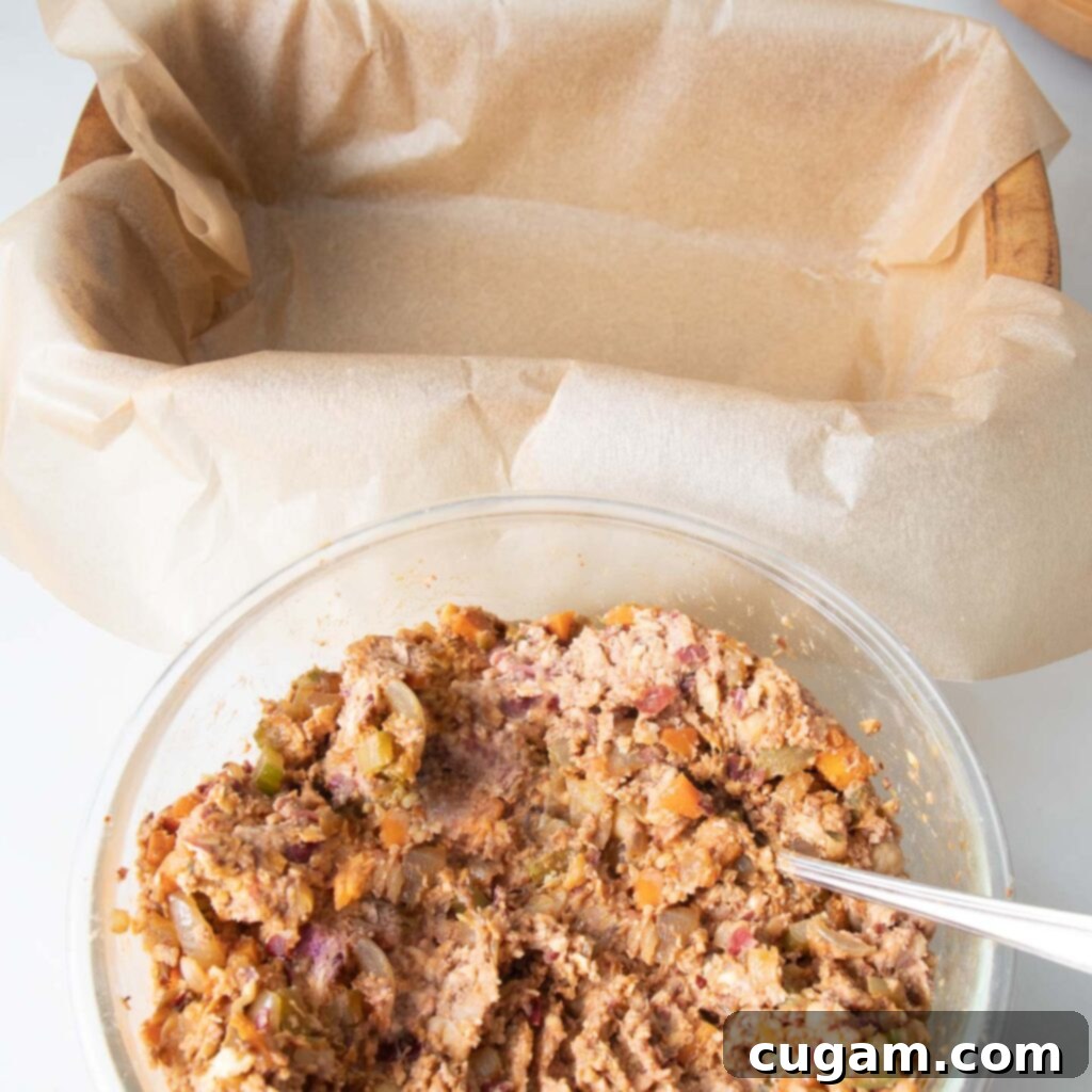 A glass bowl showcasing the perfectly mixed mashed bean mixture, alongside a loaf pan neatly lined with parchment paper, ready for baking.