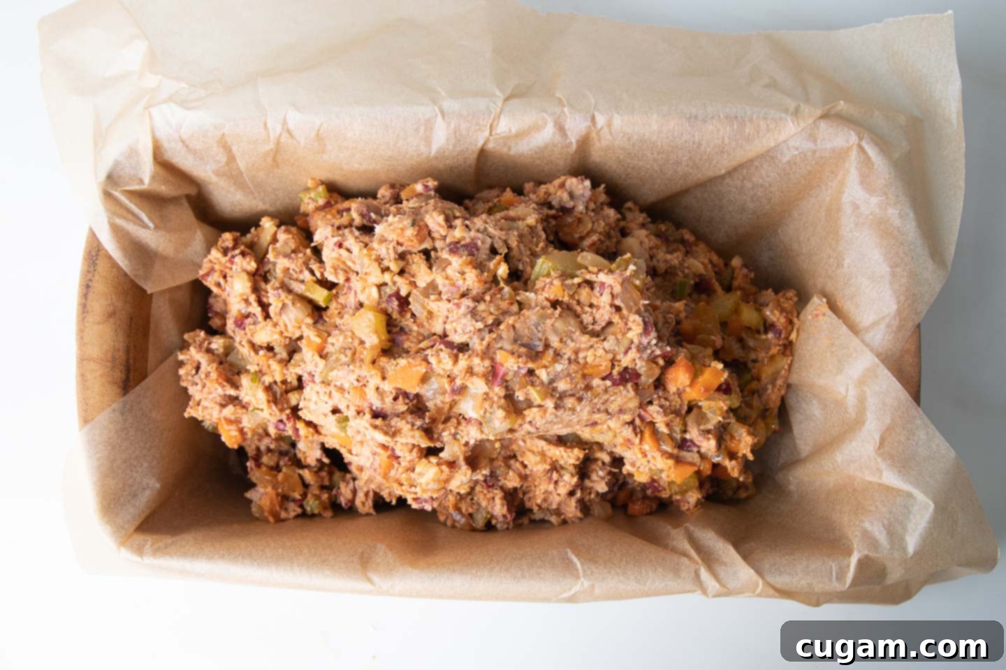 The mashed bean mixture neatly pressed into a loaf pan, lined with parchment paper, awaiting its initial bake.