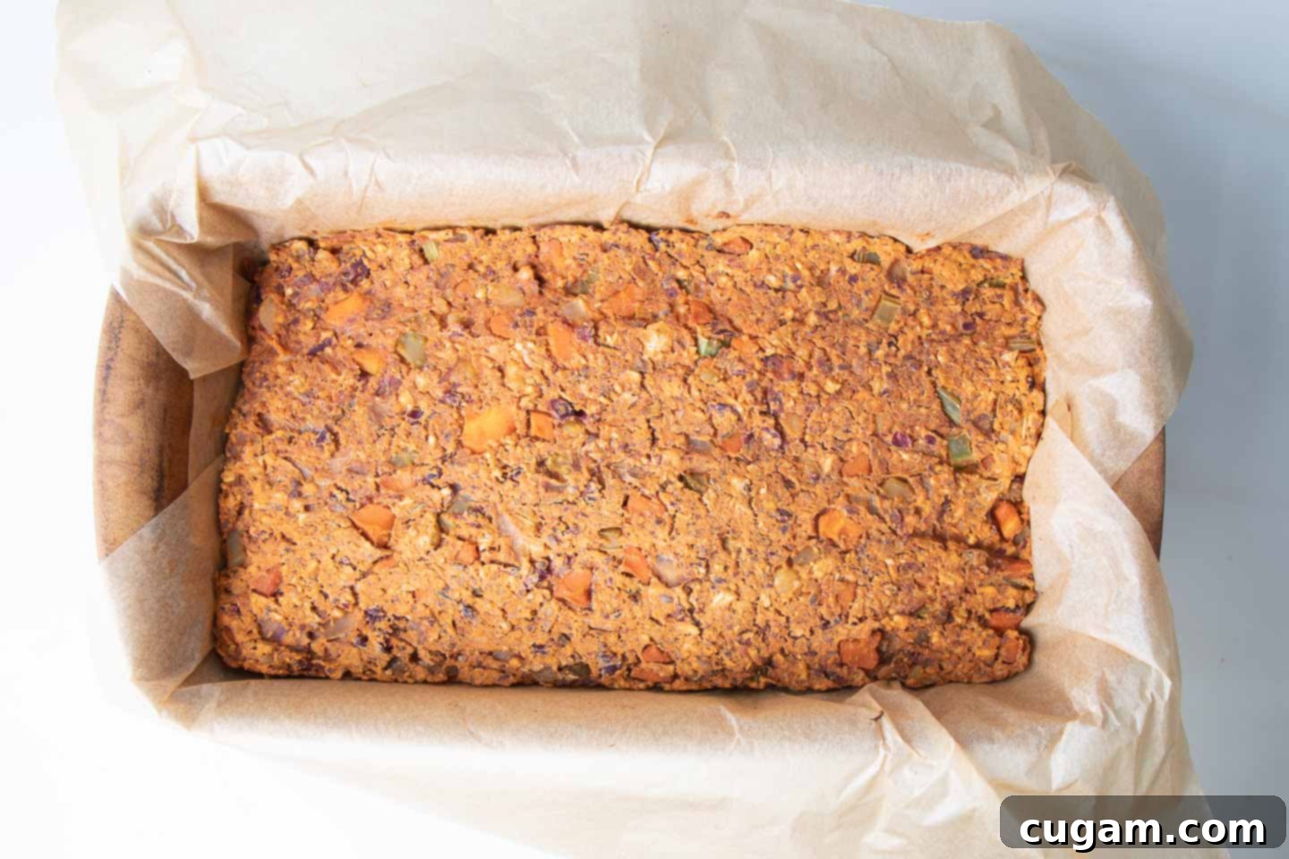The vegan meatloaf after being compressed and partially baked, showing a firm and uniform surface.