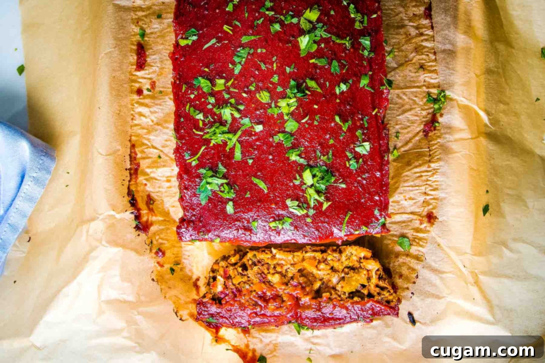 A fully baked vegan meatloaf with a rich tomato sauce, with one perfect slice cut to reveal the hearty interior texture.