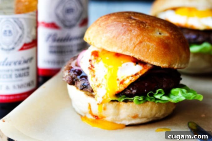 Smoky BBQ burger with runny egg yolk and Budweiser sauces in the background