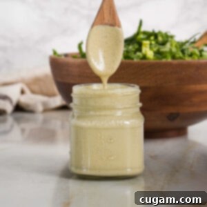 Small jar of creamy caesar dressing with a wooden spoon showing it's thickness.