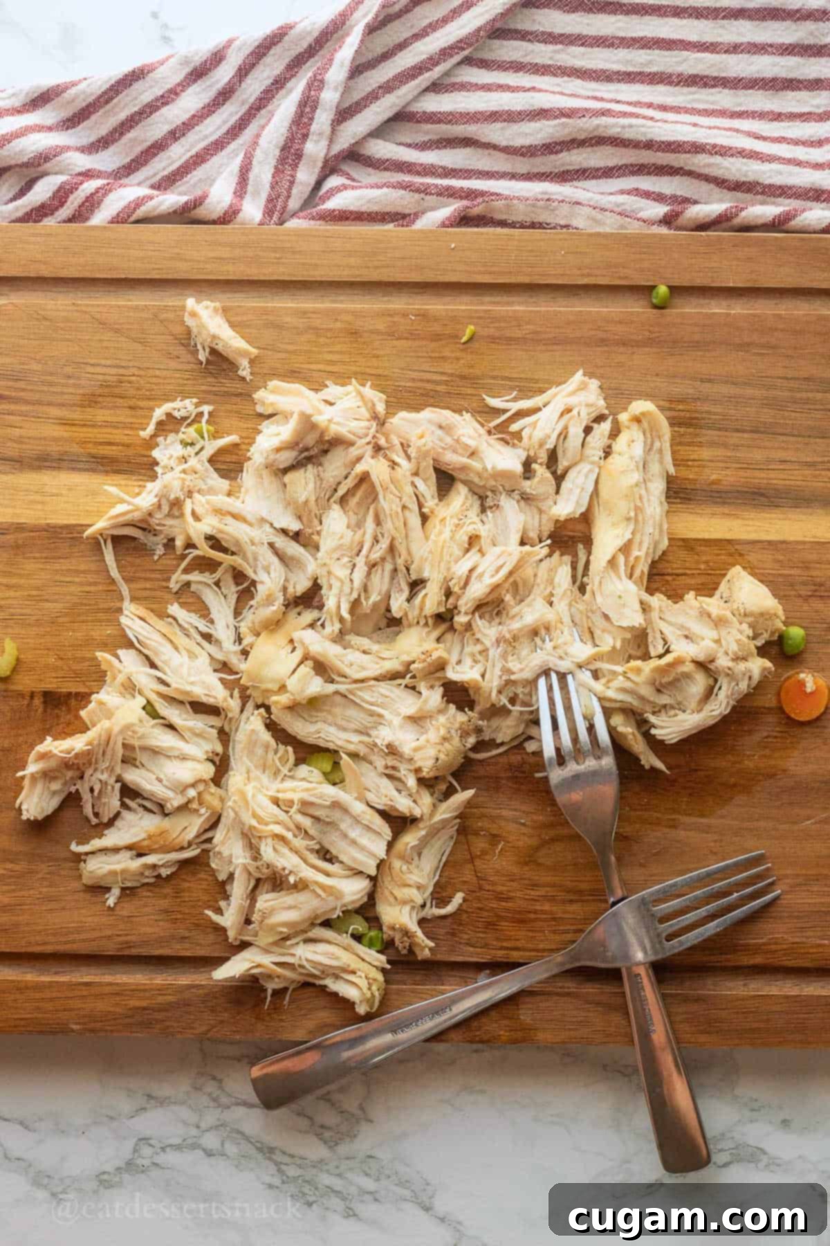 Shredded chicken on a cutting board with forks.