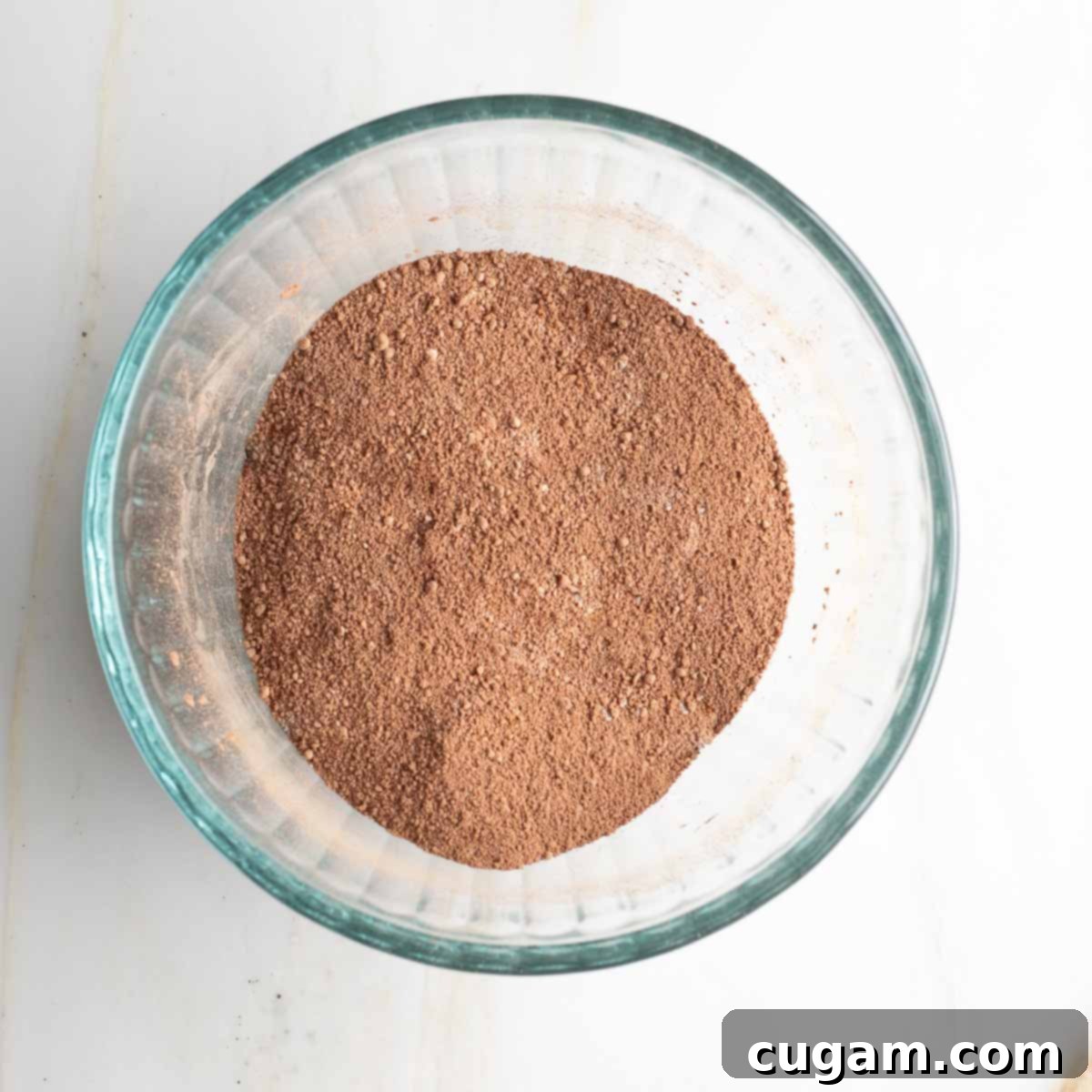 Dry brownie ingredients, including cocoa powder, almond flour, baking powder, and salt, mixed thoroughly in a small glass bowl.