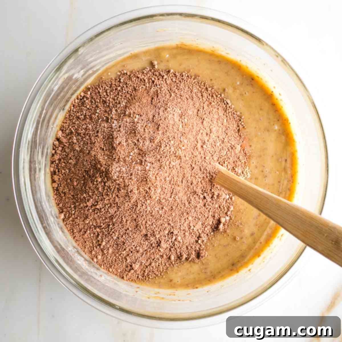 Wet ingredients combined with dry ingredients, forming the tahini brownie batter in a large glass bowl.
