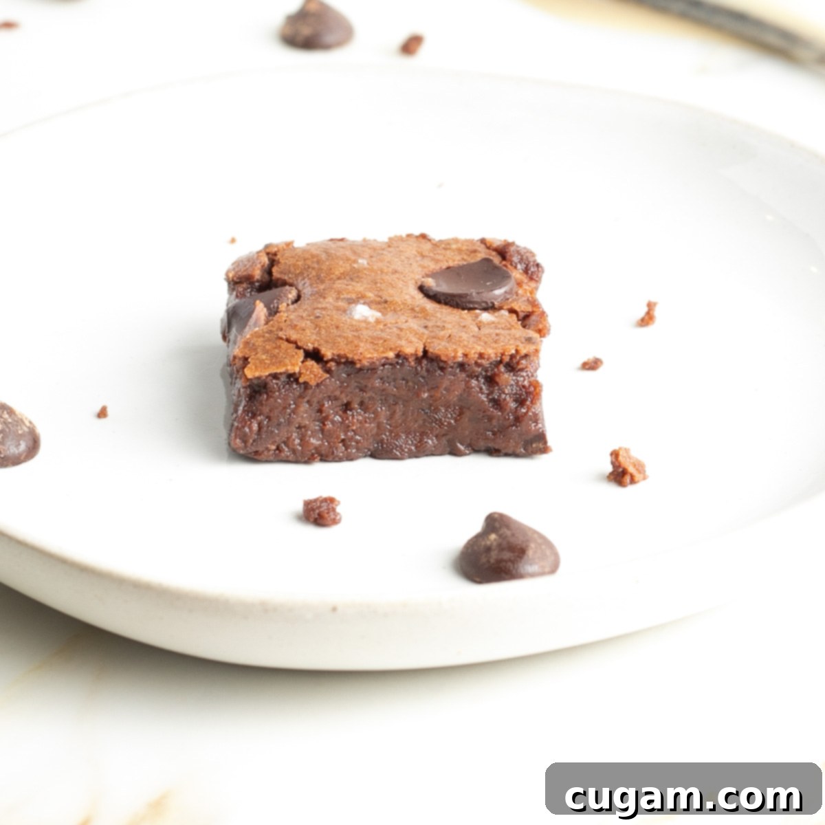 Close up side view of a rich and chocolatey tahini brownie, showcasing its fudgy texture and dark color.