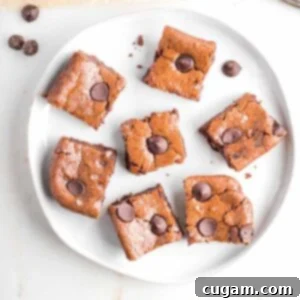 Vegan tahini brownies with chocolate chips on top, showcasing a rich, dark color and crackly surface.