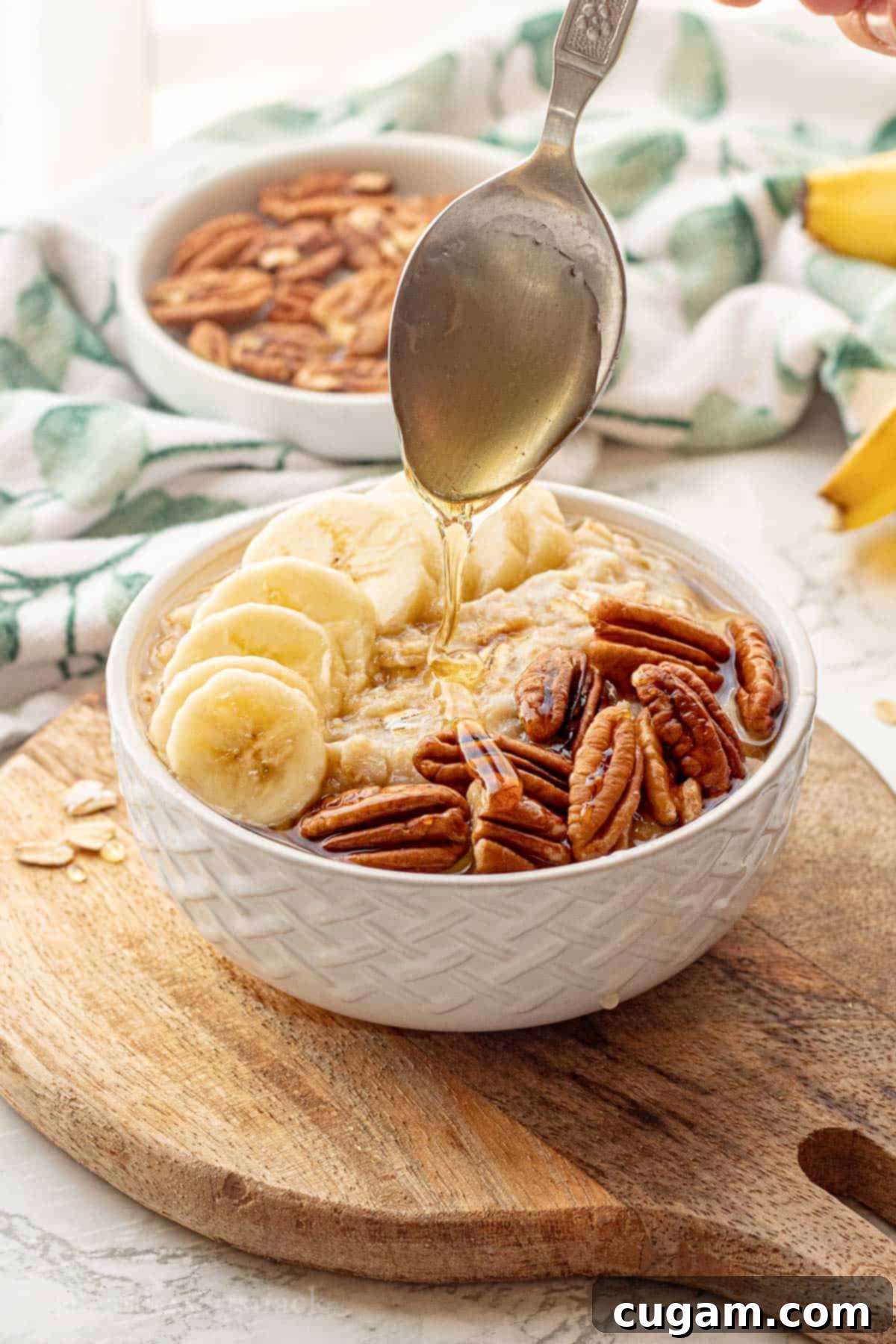 Banana Nut Oatmeal Bliss 2 Spoon drizzling honey over white bowl of banana oatmeal.