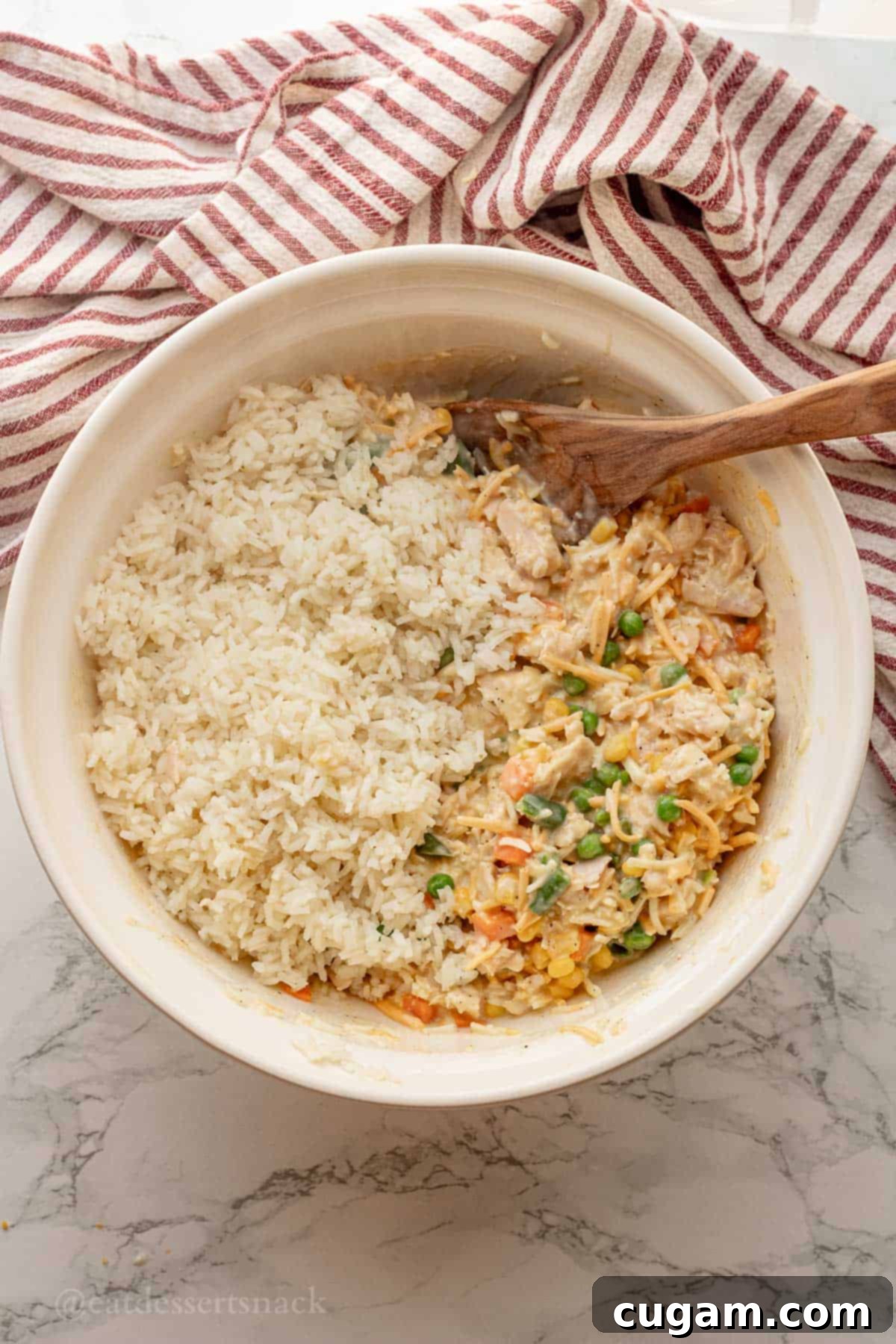 Chicken and Rice Vegetable Casserole 8 Cooked rice, veggies, and gravy in white mixing bowl with wooden spoon.