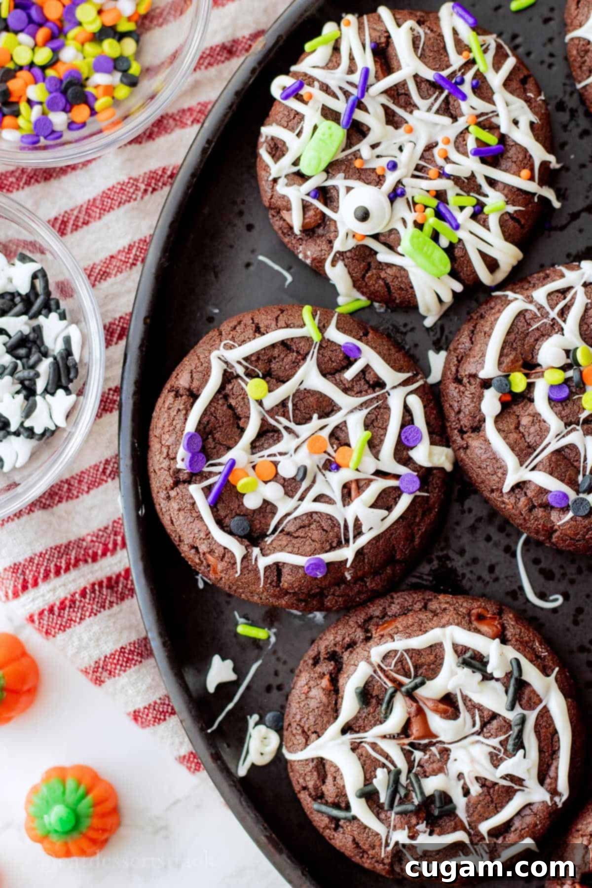 Spooky Spider Web Cookies 12 Baked spider web cookies with festive Halloween sprinkles on a black plate, ready for serving at a party.