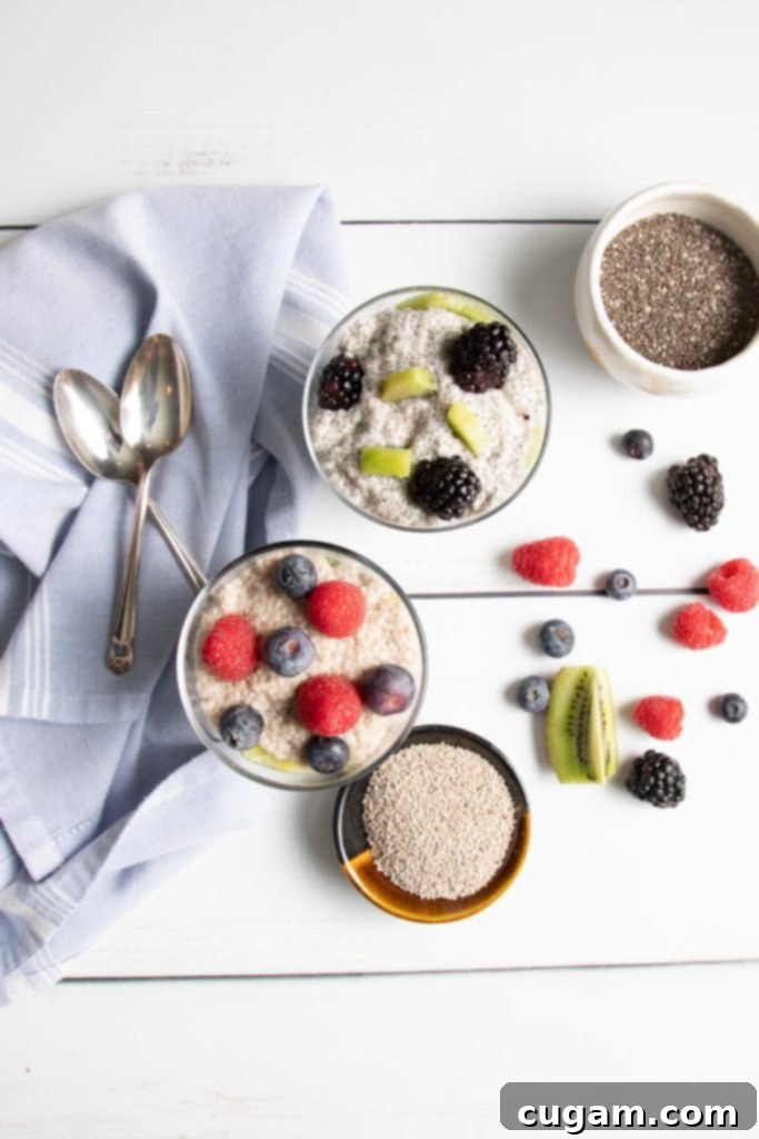 Two chia pudding parfaits in glasses, one made with white chia seeds and the other with black chia seeds, topped with fruit.