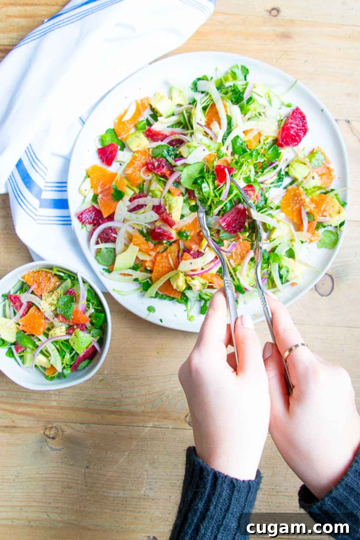 Scooping orange, fennel, avocado and onion salad into a small bowl. 