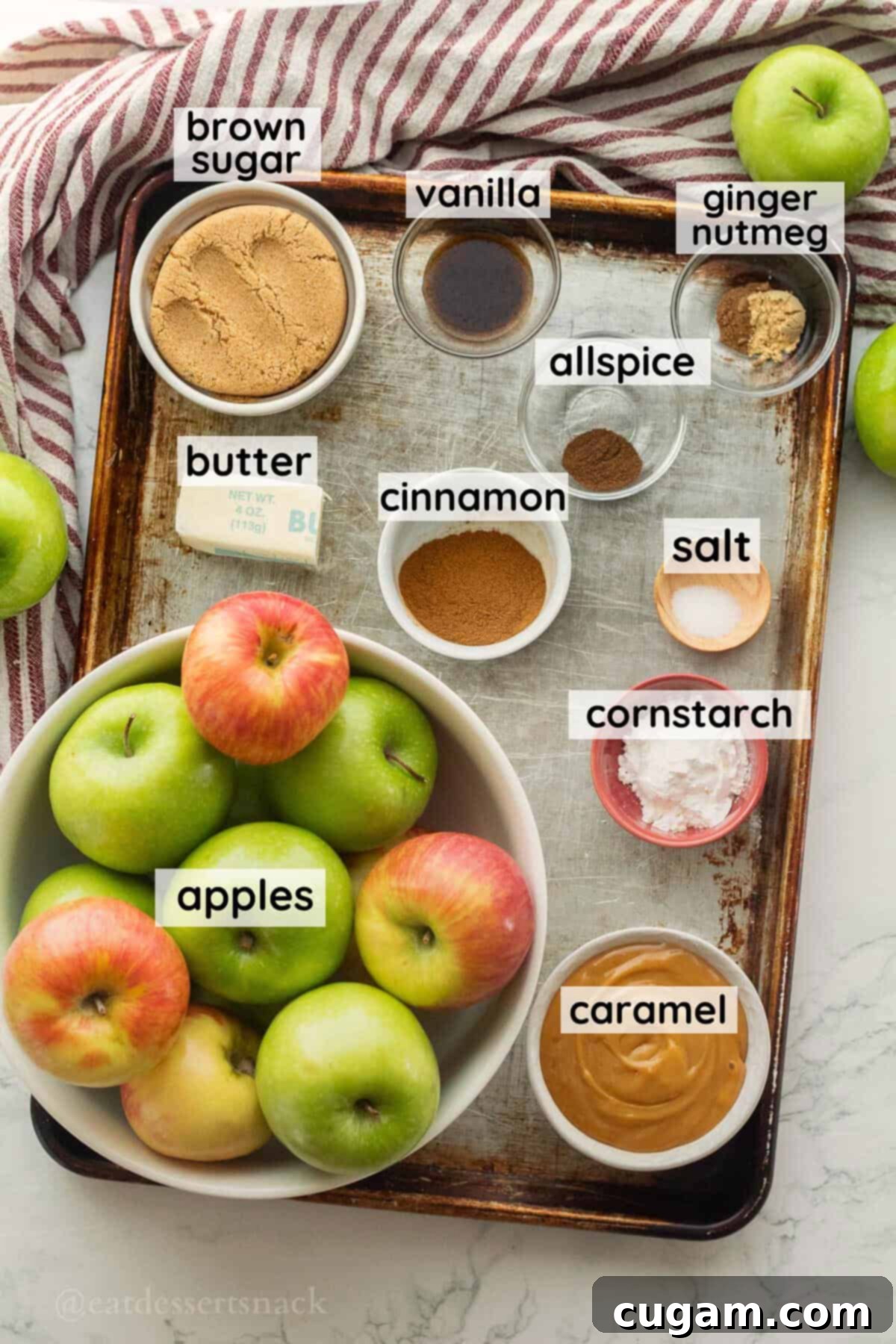 Labeled ingredients for caramel apple pie in glass dishes on metal baking pan, ready for assembly.