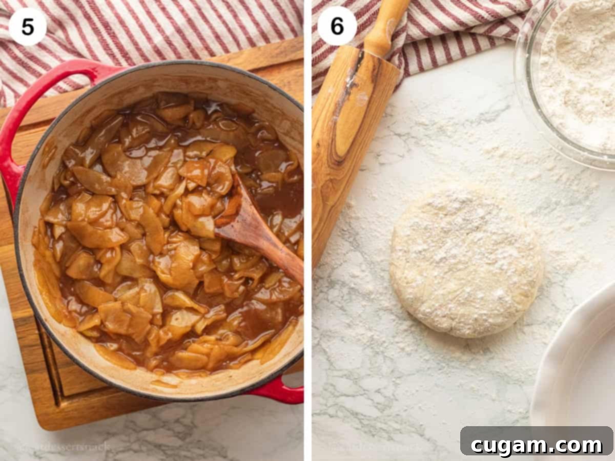 Cooked apple pie filling in red pot and raw pie dough disc with flour on marble surface.