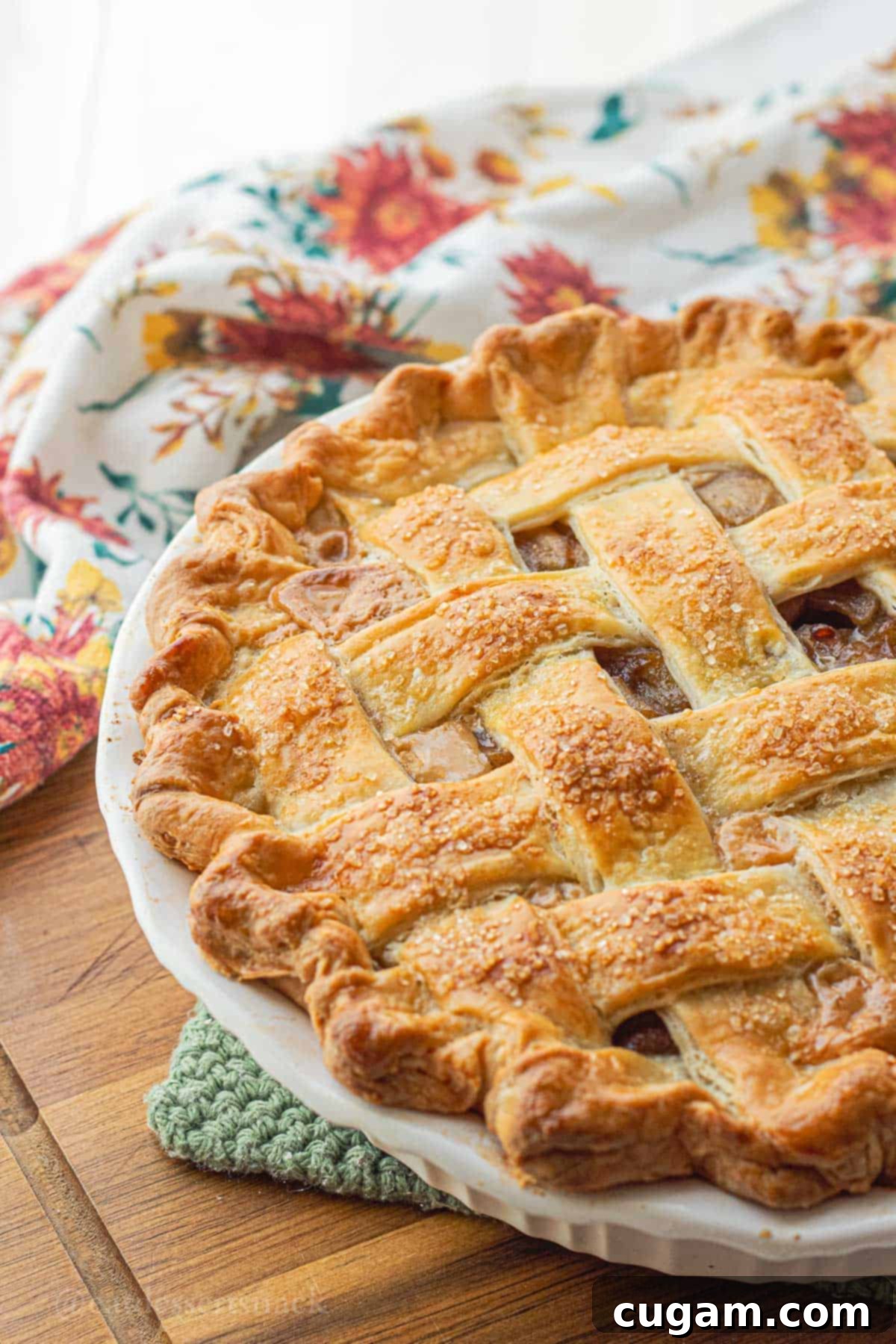 Baked unsliced dulce de leche apple pie in white pie pan, perfectly golden.