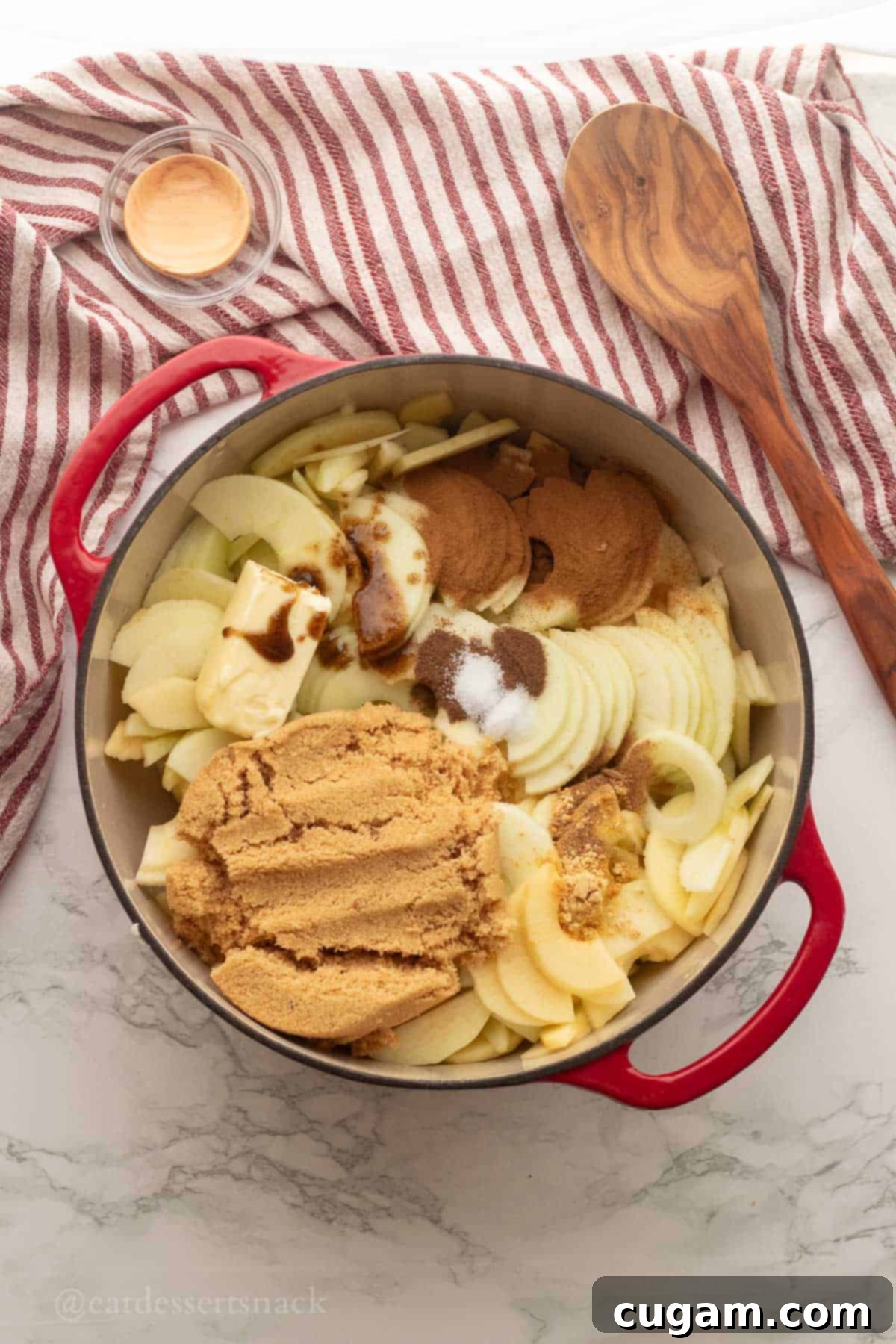 Red pan full of raw apple pie filling ingredients.