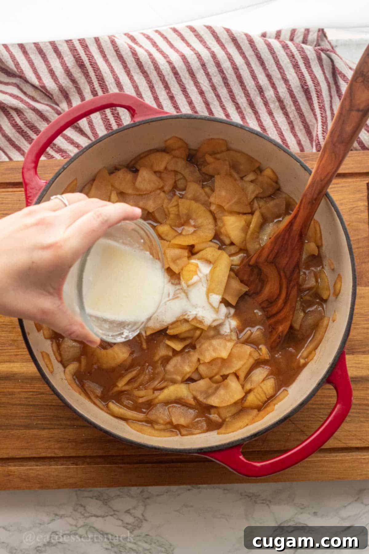 Pouring cornstarch mixture into cooked apples.