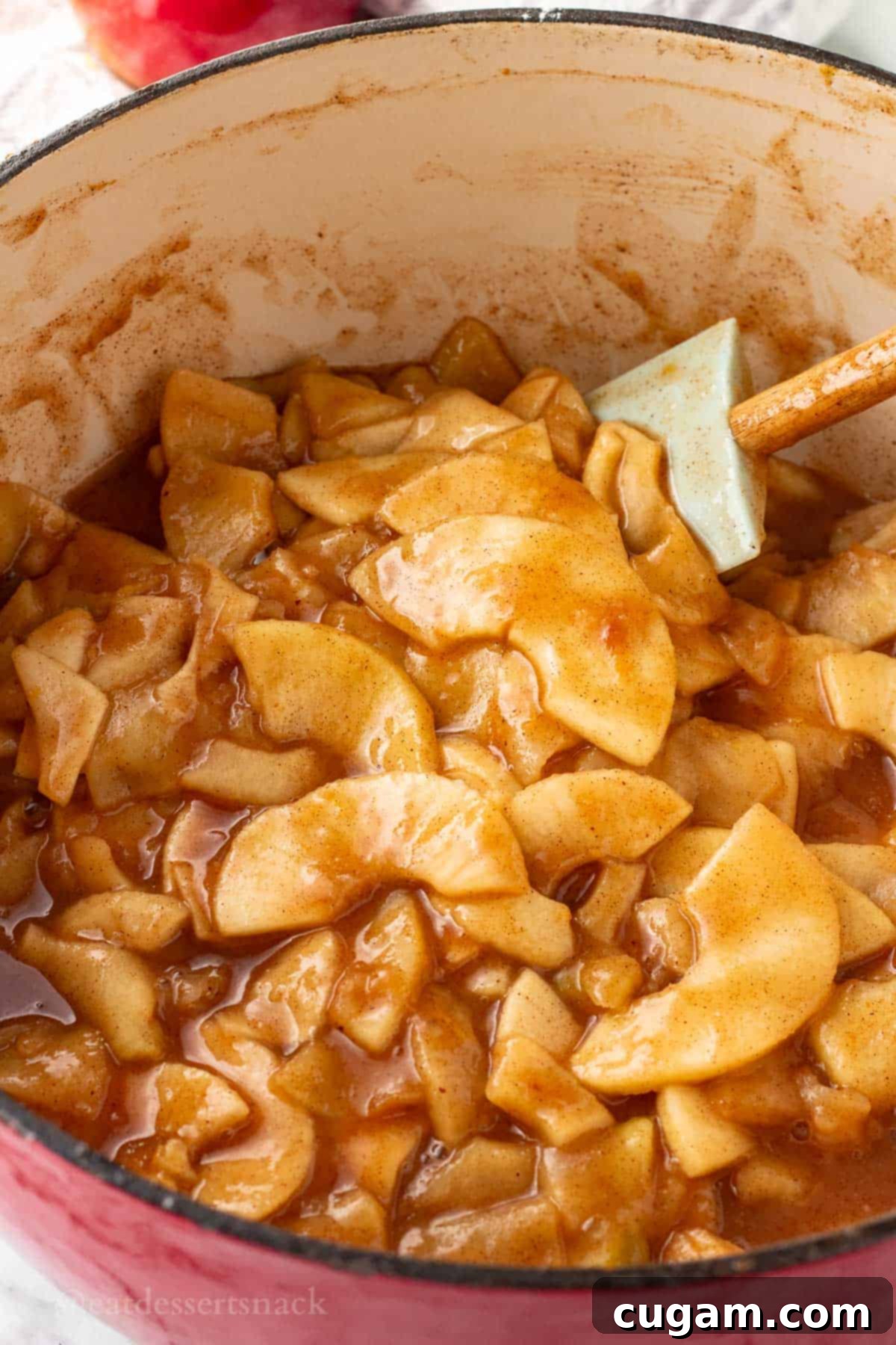 Cooked apple pie filling in red pot.