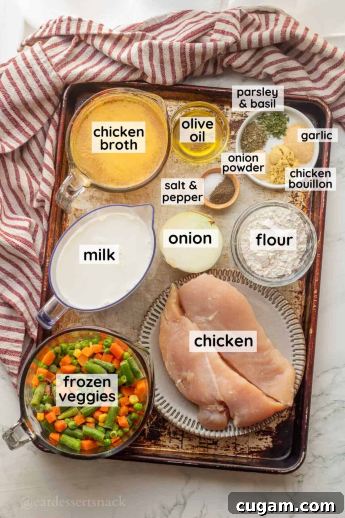 Labeled ingredients for creamy chicken and dumpling soup in glass bowls on a metal baking sheet, ready for cooking.