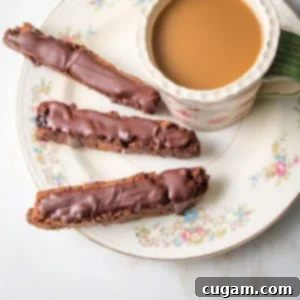flowery china plate with three chocolate covered biscotti and a cup of coffee